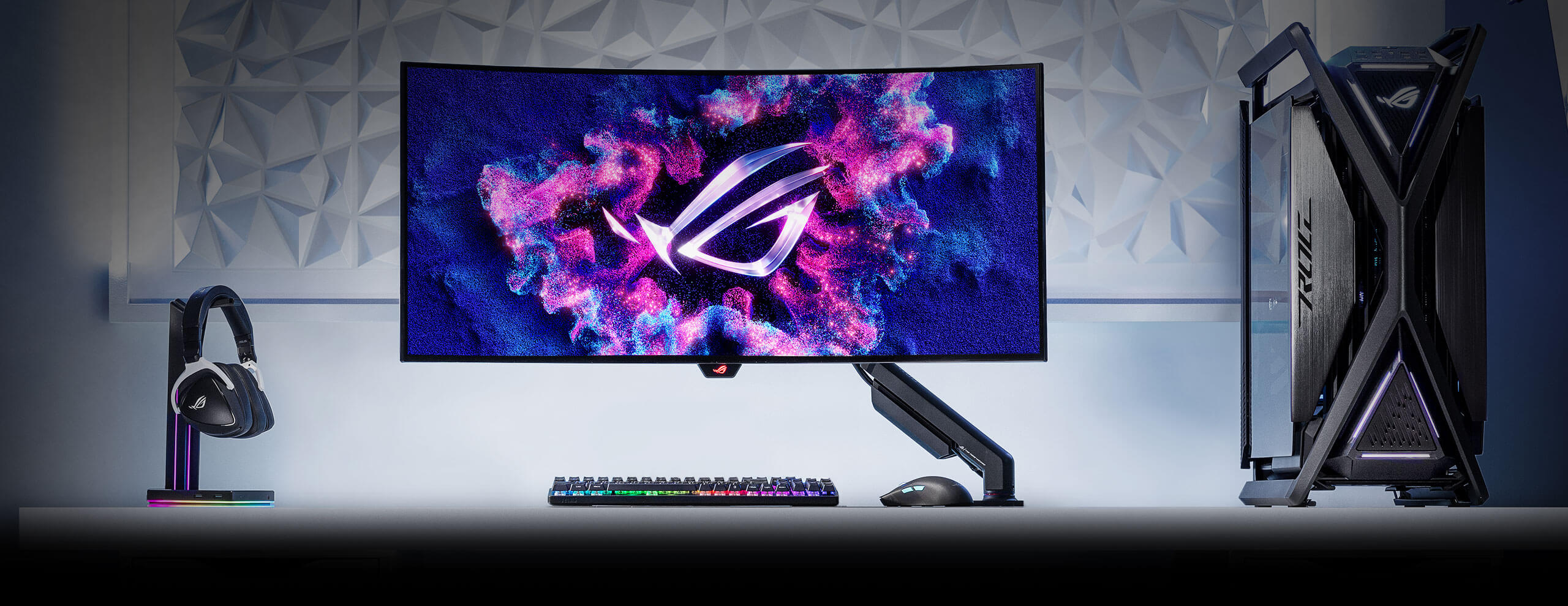 Herní sestava sestávající z monitoru ROG připevněného na rameni ROG Ergo Monitor Arm, klávesnice a myši, počítače a headsetu.